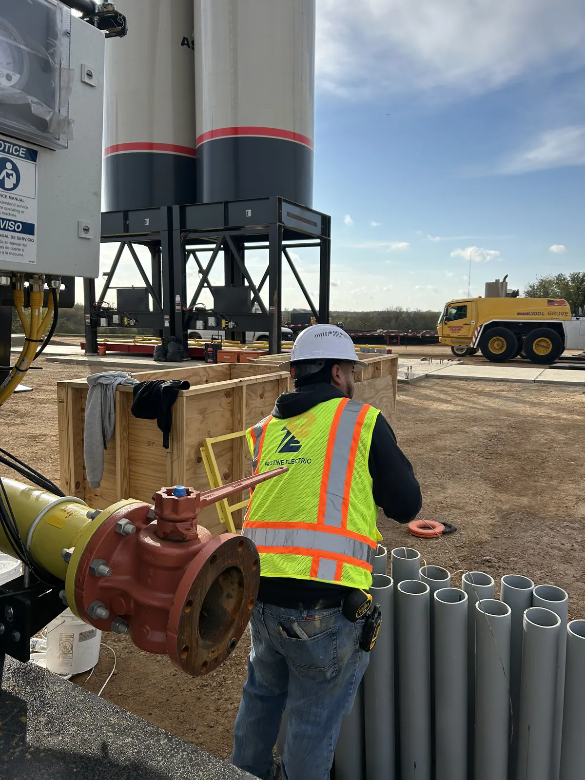 Pristine Electric electrician working beside industrial equipment and conduit on a job site