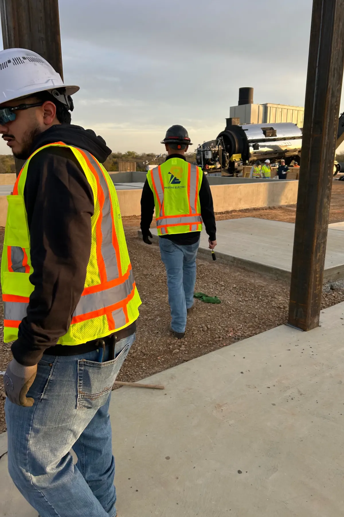 Pristine Electric electricians in safety vests walking a commercial job site